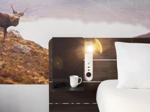 a hotel room with a bed and a cup and a cow at Novotel Edinburgh Centre in Edinburgh +164 photos