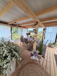 a wooden deck with a table and chairs and flowers at Mazligzdiņa in Višķi