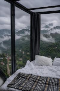 a bed in a room with a large window at Lazord Glass Bungalow Trabzon in Geçit
