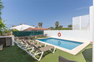a swimming pool with chairs and an umbrella at Villa Sea Lights 89b in Son Bou