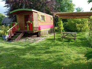 a tiny house and a picnic table in a yard at Roulotte Anaîs in Grandcourt