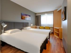 a hotel room with two beds and a tv at ibis Hotel Würzburg City in Würzburg