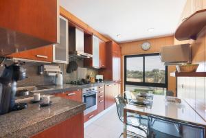 a kitchen with wooden cabinets and a large window at Parque Atlântico Apartment in Quarteira