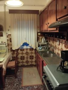 a kitchen with wooden cabinets and a sink and a window at Fiorela Gest House in Kalabaka +22 photos