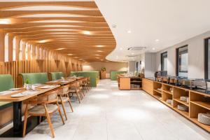 a restaurant with wooden ceilings and tables and green chairs at Lords CBC Plaza Chitwan in Bharatpur