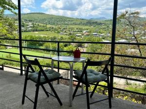 a table and two chairs on a balcony with a view at Dusheti Retreat - Authentic Georgian Living in Dushetʼi