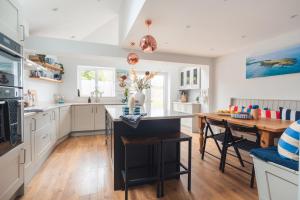 a kitchen with white cabinets and a wooden table at Gerallt in Pwllheli +20 photos
