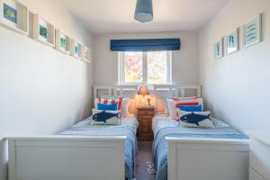 two beds in a small room with a window at Gerallt in Pwllheli