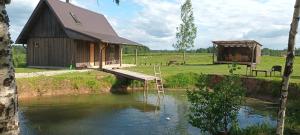 a cabin next to a river with a wooden bridge at Staltbrieži in Ratnieki