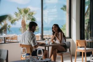 a man and woman sitting at a table in a restaurant at Bahia Principe Escape Tenerife - Hyatt Inclusive Collection in Adeje