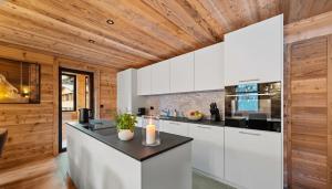 a kitchen with white cabinets and a wooden ceiling at Chalet Dents Blanches - Latitude Champéry in Champéry