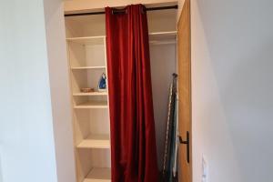 a closet with a red curtain and shelves at Bidart, maisonnette sur les Pyrénées in Bidart +9 photos