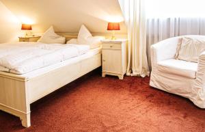 a bedroom with a white bed and a chair at Herzog Friedlich Hotel Garni in Friedrichstadt