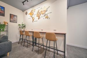a bar with stools and a world map on the wall at Urban Pod Capsule Hostel in Bangkok