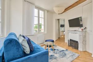 ein blaues Sofa in einem Wohnzimmer mit Kamin in der Unterkunft C'Châtelet in Chartres + 12 Fotos