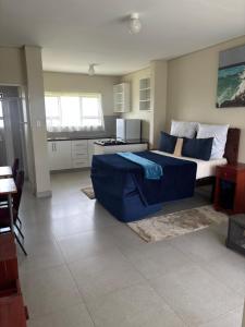 a living room with a blue couch and a kitchen at Hlalanathi Lodges - Wagendrift Farm in Estcourt +20 photos