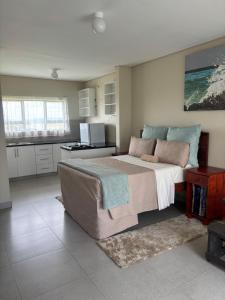 a bedroom with a large bed and a kitchen at Hlalanathi Lodges - Wagendrift Farm in Estcourt