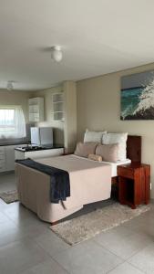 a bedroom with a large bed and a kitchen at Hlalanathi Lodges - Wagendrift Farm in Estcourt