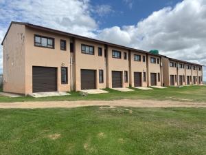 a large building with doors and windows on a field at Hlalanathi Lodges - Wagendrift Farm in Estcourt
