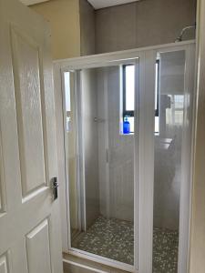 a shower with a glass door in a bathroom at Hlalanathi Lodges - Wagendrift Farm in Estcourt