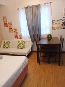 a room with two beds and a table and a desk at Lois Ann Condo in Pontud
