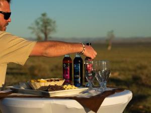 a man holding a table with wine bottles and wine glasses at Namib Naukluft Lodge in Solitaire