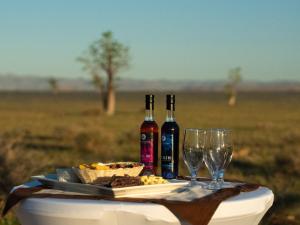 a table with two bottles of wine and wine glasses at Namib Naukluft Lodge in Solitaire