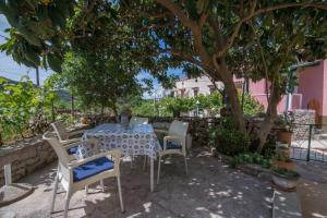 un tavolo e delle sedie sotto un albero di Roberto Apartments a Veli Lošinj (Lussingrande)