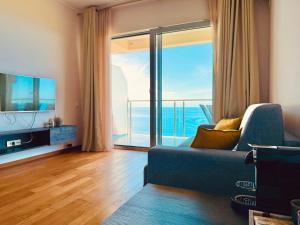 a living room with a blue couch and a large window at Altezza Premium Breathtaking Sea Views in Budva