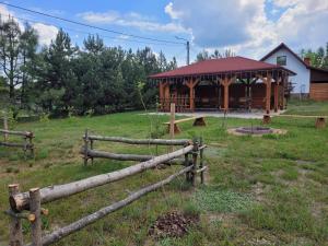 a wooden cabin with a fence in a field at Domki Strumieniowa in Wólka Tanewska