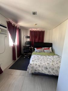 a bedroom with a bed with red curtains and a desk at Casa Rufina in Taluc