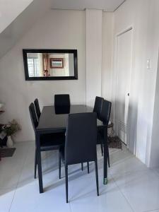 a dining room table with black chairs and a mirror at Casa Rufina in Taluc