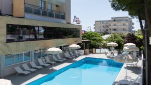 a swimming pool with chairs and umbrellas next to a building at Hotel Simon in Gatteo a Mare