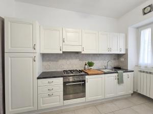 a white kitchen with white cabinets and a stove at Da nonno Carlo Lakeview - By BorgoLago in Capodimonte