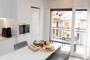 a white living room with a table with a bowl of fruit on it at Sky Biescas II by BeValle in Biescas