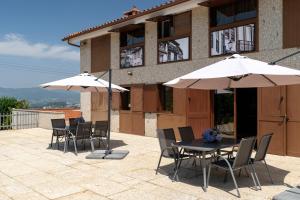 a patio with tables and umbrellas in front of a building at Casas da Aldeia da Graça in Guimarães