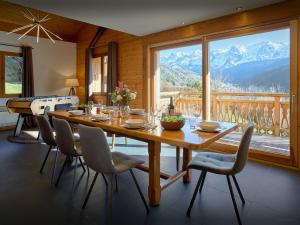 a dining room with a table and chairs and a large window at Chalet Aravista - OVO Network in Le Grand-Bornand