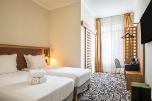 a hotel room with two beds and a window at Best Western Hotel Centre Reims in Reims