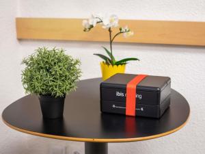 a briefcase on a table with plants and flowers at ibis Nogent Sur Marne RÉNOVÉ EN 2025 in Nogent-sur-Marne