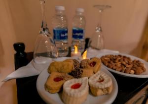 a plate of pastries on a table with candles and drinks at Sahara Nomadic Luxury Camp in Merzouga