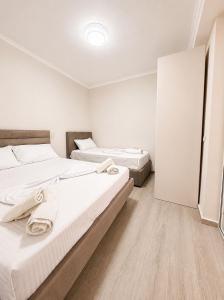two beds in a room with white walls and wooden floors at Deon in Vlorë