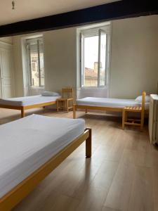 a room with three beds and two windows at Gîte de la cathédrale 2 in Condom