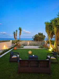 a backyard with a lawn with chairs and palm trees at Ostria Beach House in Órmos Marathokámpou