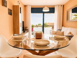 a dining room with a glass table and white chairs at Apartamento L'Eucaliptus, Delta del Ebro in Amposta