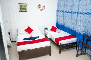 two beds in a room with red and blue curtains at Alles garden New Seaside in Trincomalee