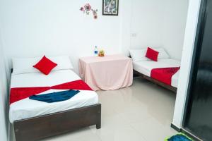 two beds with red pillows and a table in a room at Alles garden New Seaside in Trincomalee