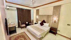 a bedroom with a bed and a desk and a television at Shelton's Rezidor Peshawar in Peshawar