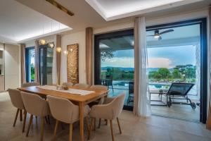 a dining room with a table and chairs and a balcony at Villa Elementa Krk - Luxury Four Elements Experience in Krk