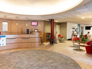a lobby with a waiting room with red chairs at ibis Auch in Auch