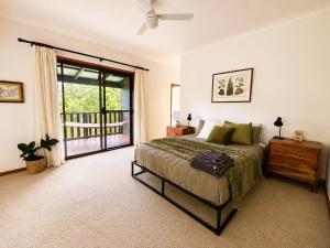 a bedroom with a bed and a sliding glass door at Thrums Bush Retreat in Upper Orara